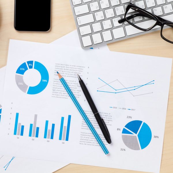 Pen, pencil, phone and computer keyboard with printed graphs on paper. Review of the Year 2019