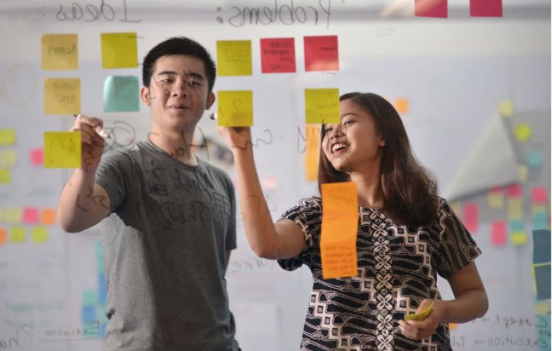 Two students working away on a whiteboard