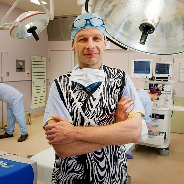 Professor Zsolt Balogh standing an operating theatre with medical equipment behind him