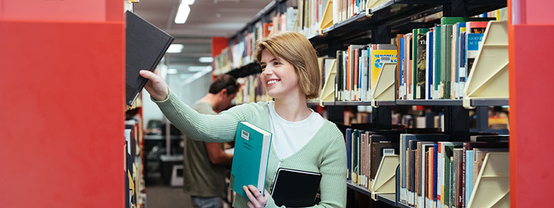 A student getting a book from the library shelf