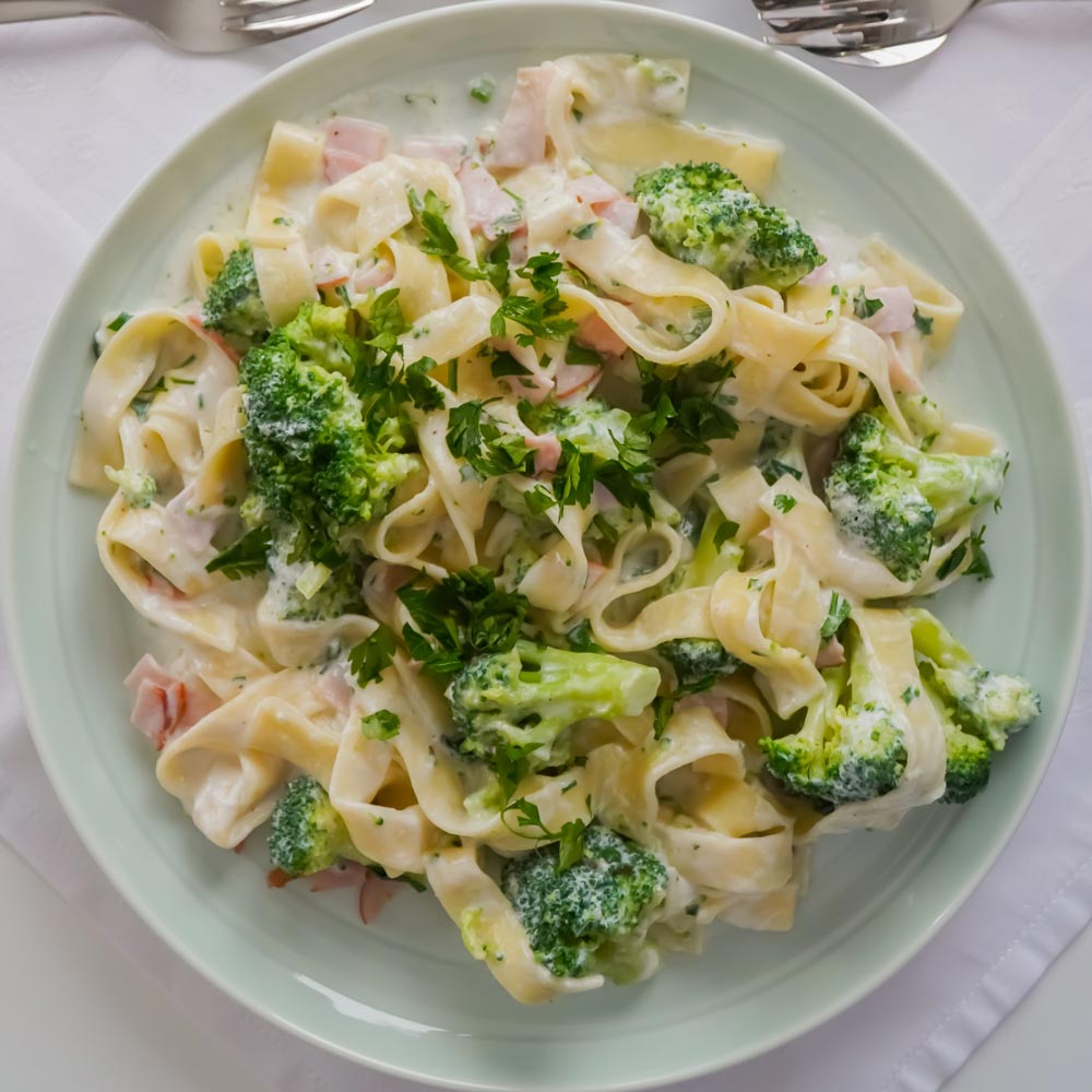 Bowl of bacon carbonara pasta with broccoli throughout.