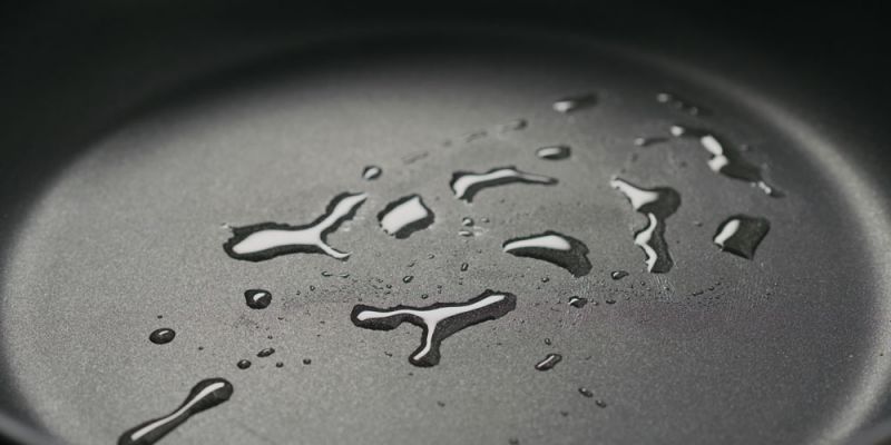 The surface of a non-stick pan with some waster droplets on it. 