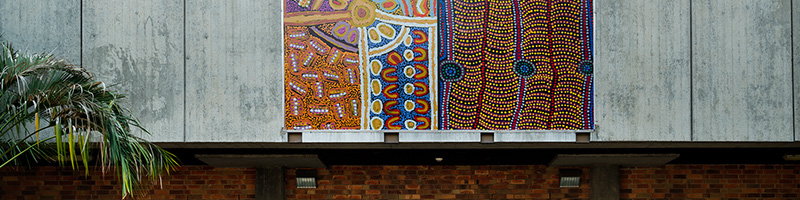 Some Aboriginal artwork hangs on a wall, it features blue and earthy colours