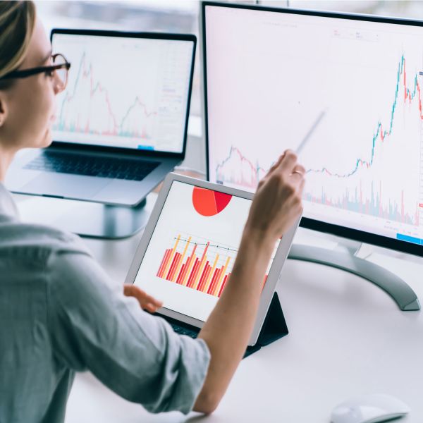 image of woman using a range of computers to look at graphs