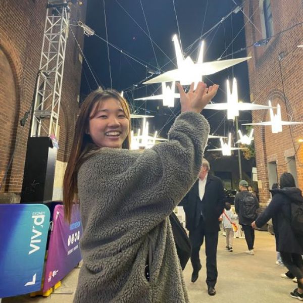 Woman standing in laneway at night pointing to light paper crane at vivid festival