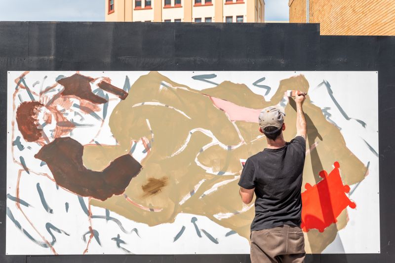 Man painting a mural on a black wall