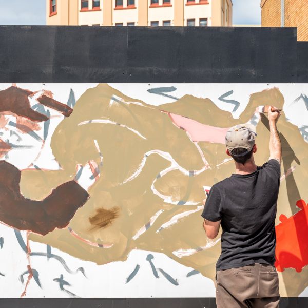 Man painting a mural on a black wall
