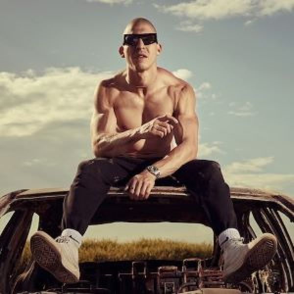 Music artist chillinit sitting on the top of a car wearing sunglasses