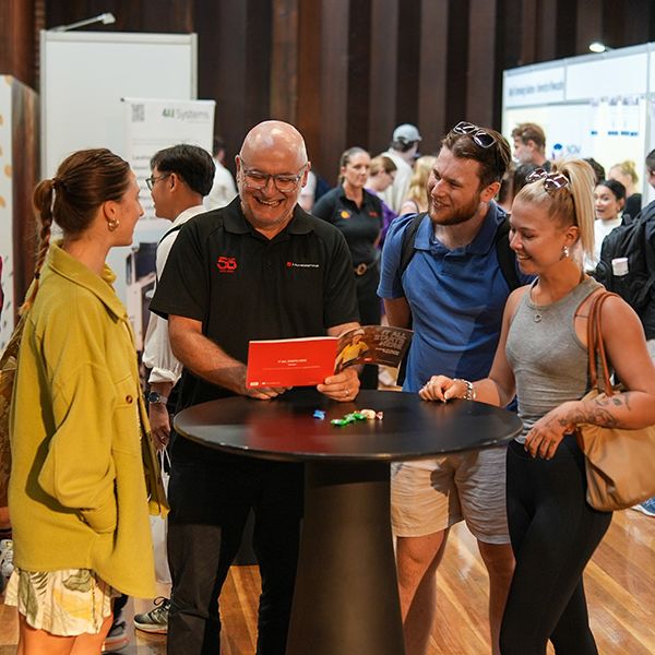 Four people standing around a table and talking.