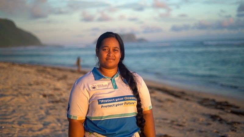 Fimareti looking to camera with a beautiful beach backdrop in Samoa at sunset