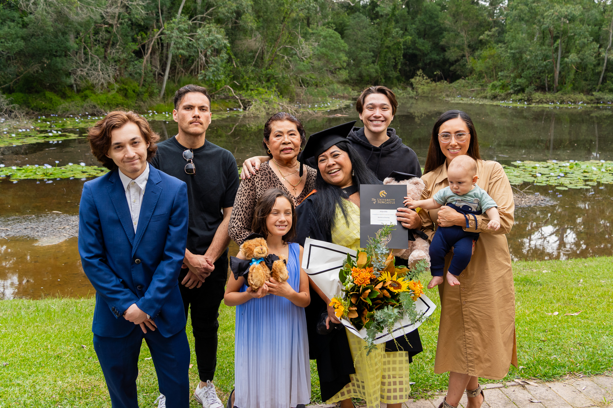 Graduate surrounded by their family near a pond
