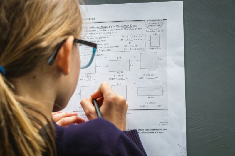 View of young girl with glasses from behind working on school work