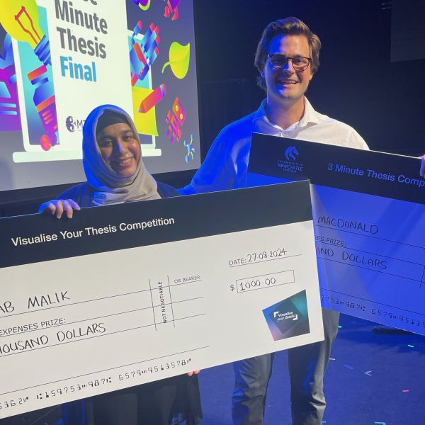 Zanab Malik and Jake MacDonald with their first place cheques on stage. In three minutes or less: Creative pitches take first place at competitive research finals 