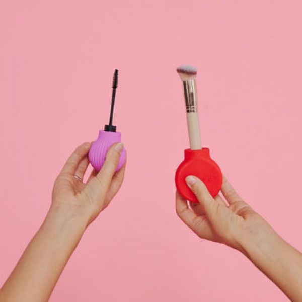 Two hands holding BYSTORM Beauty Tools against a pink background.