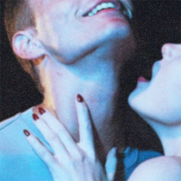 A close-up of two people with heads tilted back, one gently touching the other's neck with red-painted nails.