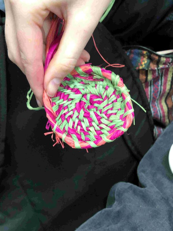 A tiny brightly coloured woven basket in someone's hand