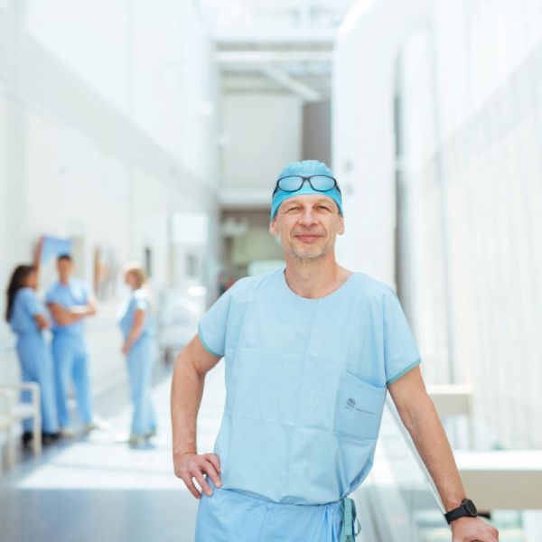 Man dressed in scrubs smiling for the camera