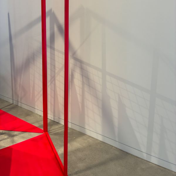 a glimpse of a red structure forming shadows against a white wall