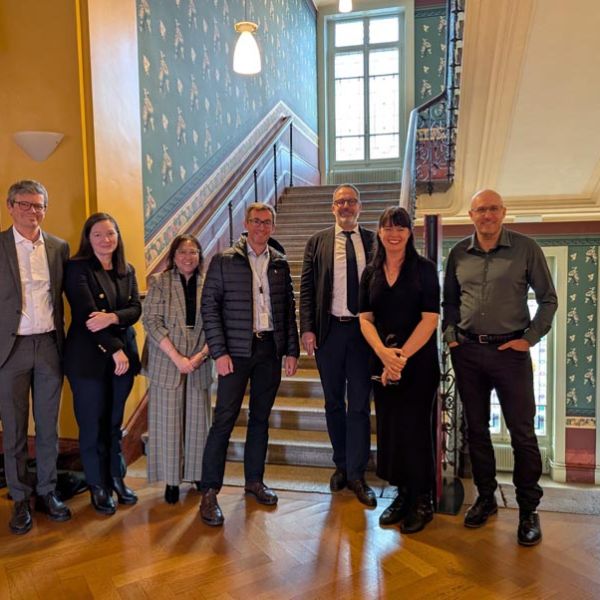 A group of people smiling in front of a staircase