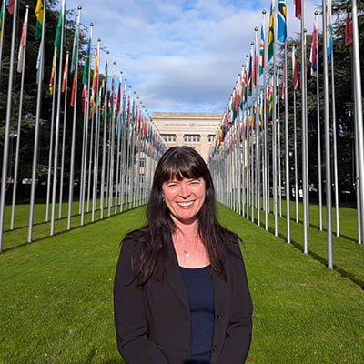 A woman standing in front of a building with flags