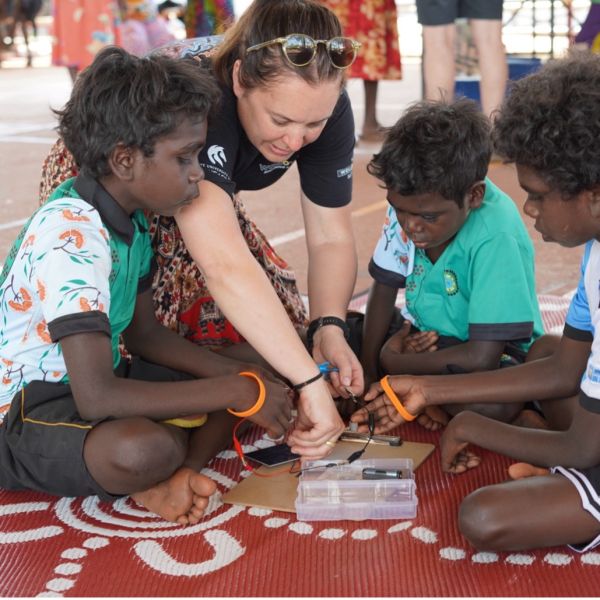 UNiversity staff sitting with students from Our Lady of the Sacred Heart Thamarrurr Catholic College working on a STEM activity. Where Culture meets STEM: Empowering future leaders in Wadeye.