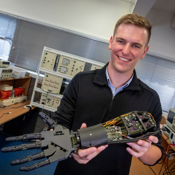 man holding robotic arm. Local Engineering graduate lands an Ivy League spot