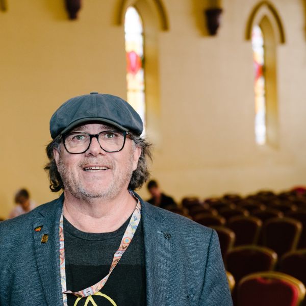 Head and shoulders shot of Professor Maynard smiling in Empire Church Theatre with stained glass windows, Toowoomba. 65,000 Years of Place and Memory  