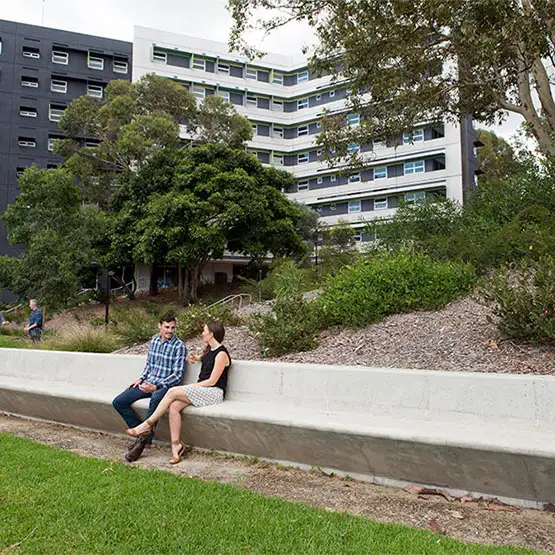 Two people sitting on a bench surrounded by trees
