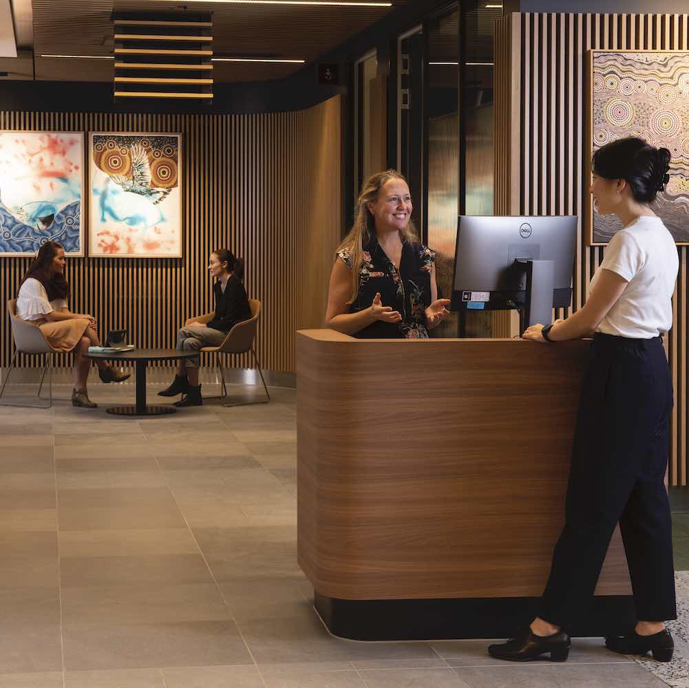 Two people standing and talking in the Central Coast Clinical School building