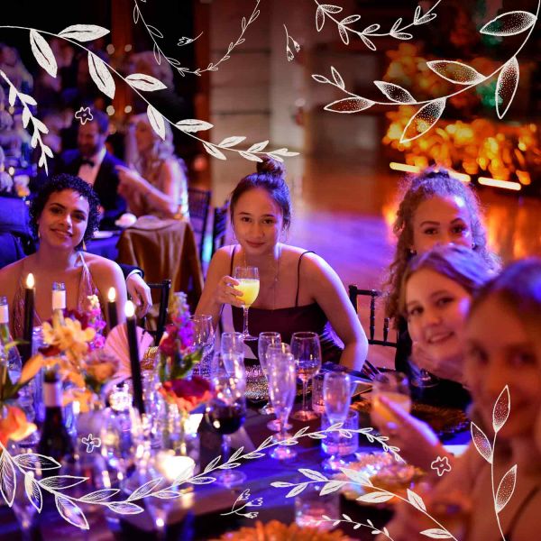 Group of students sitting at table dressed up at Summer Ball.