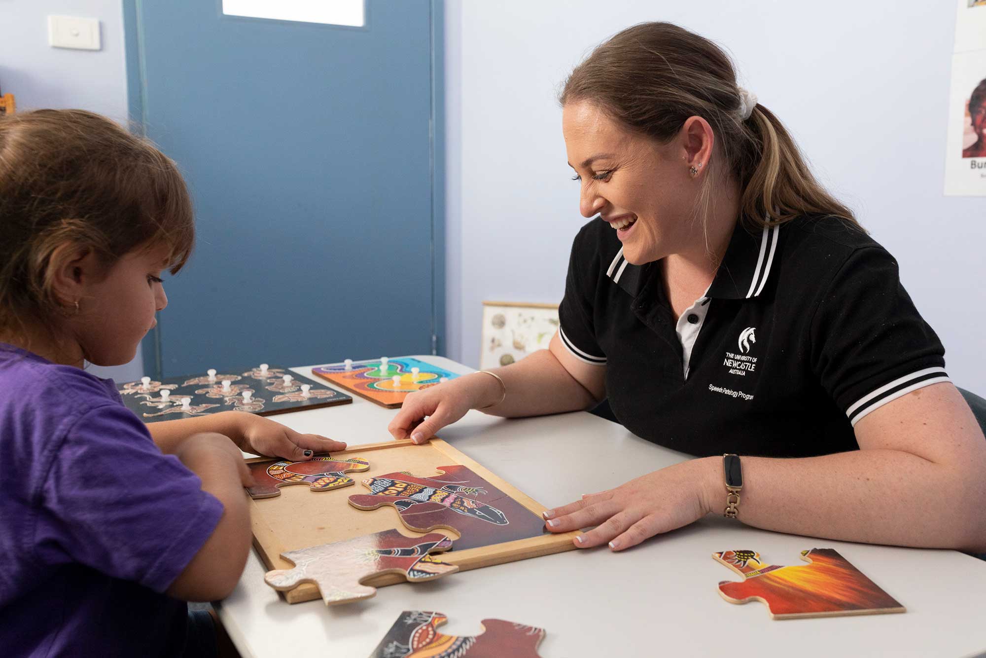 Speech pathology student playing with a puzzle with young patient.