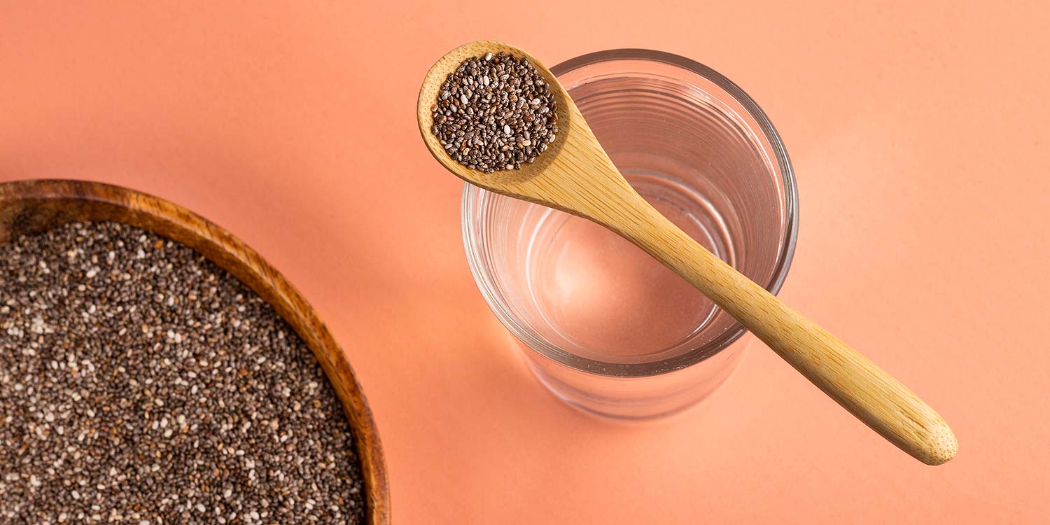 Spoonful of chia seeds resting on a cup of water