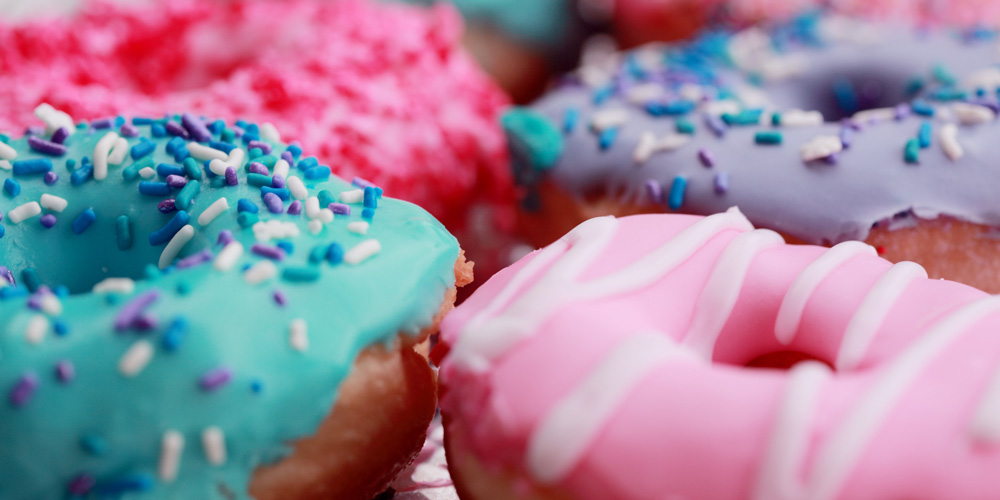 Four doughnuts next to each other, two pink, one purple and one blue.