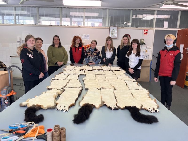 High school students looking at possum skins laid out on a table