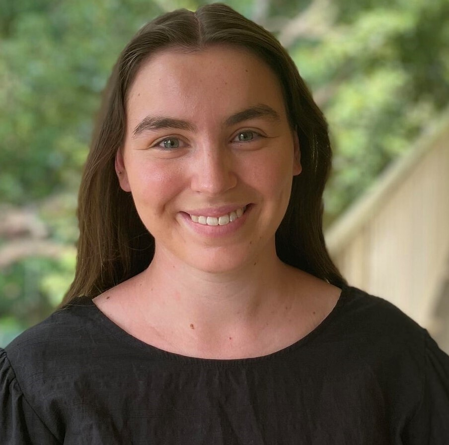 Olivia is pictured smiling in a black t-shirt 