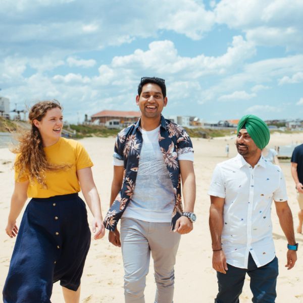 Three students walking on a beach, laughing