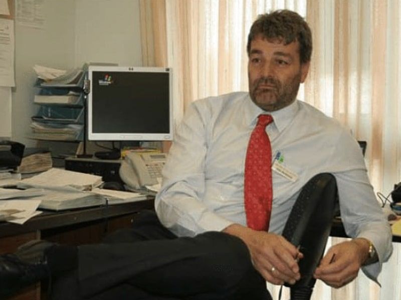 John pictured sitting at his school office desk, chatting
