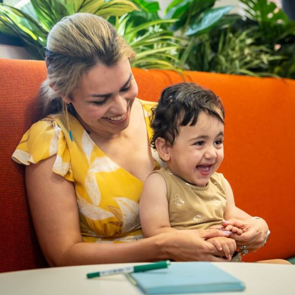 Dr Leila Momenzadeh sits with her child, both of them smiling. Evidence of equity action puts University of Newcastle first in Australia