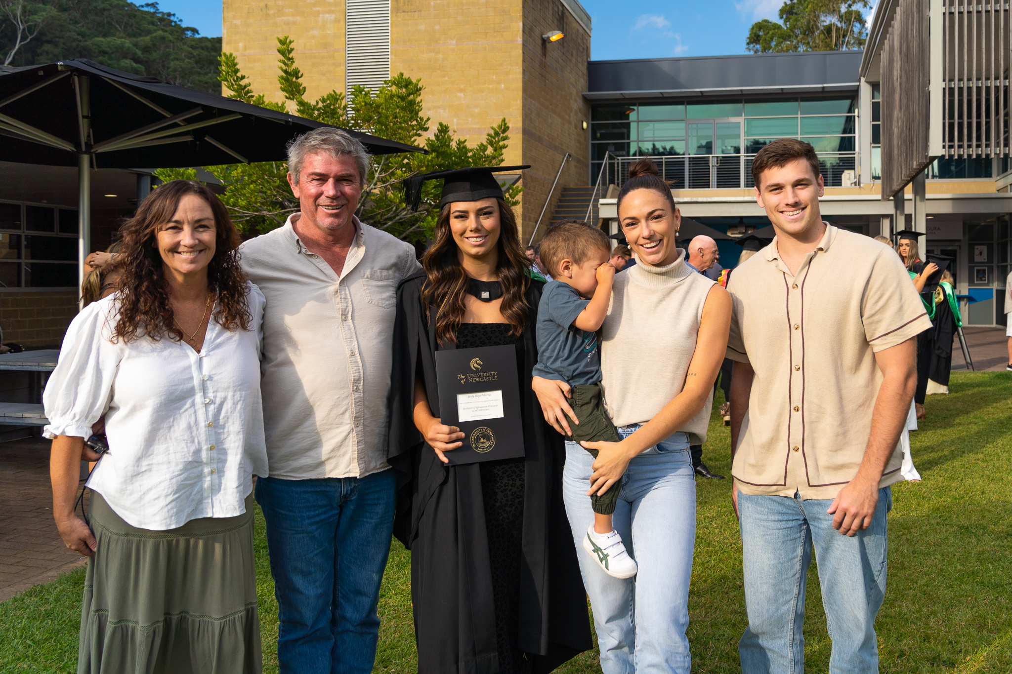 Graduate stands in front of the library with her family