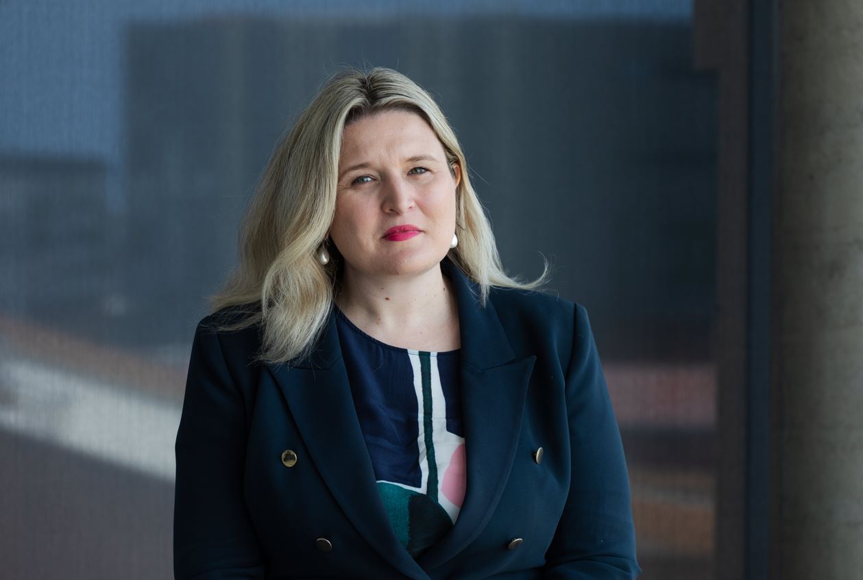 Dr Kcasey McLaughlin stands head and shoulders in front of the camera