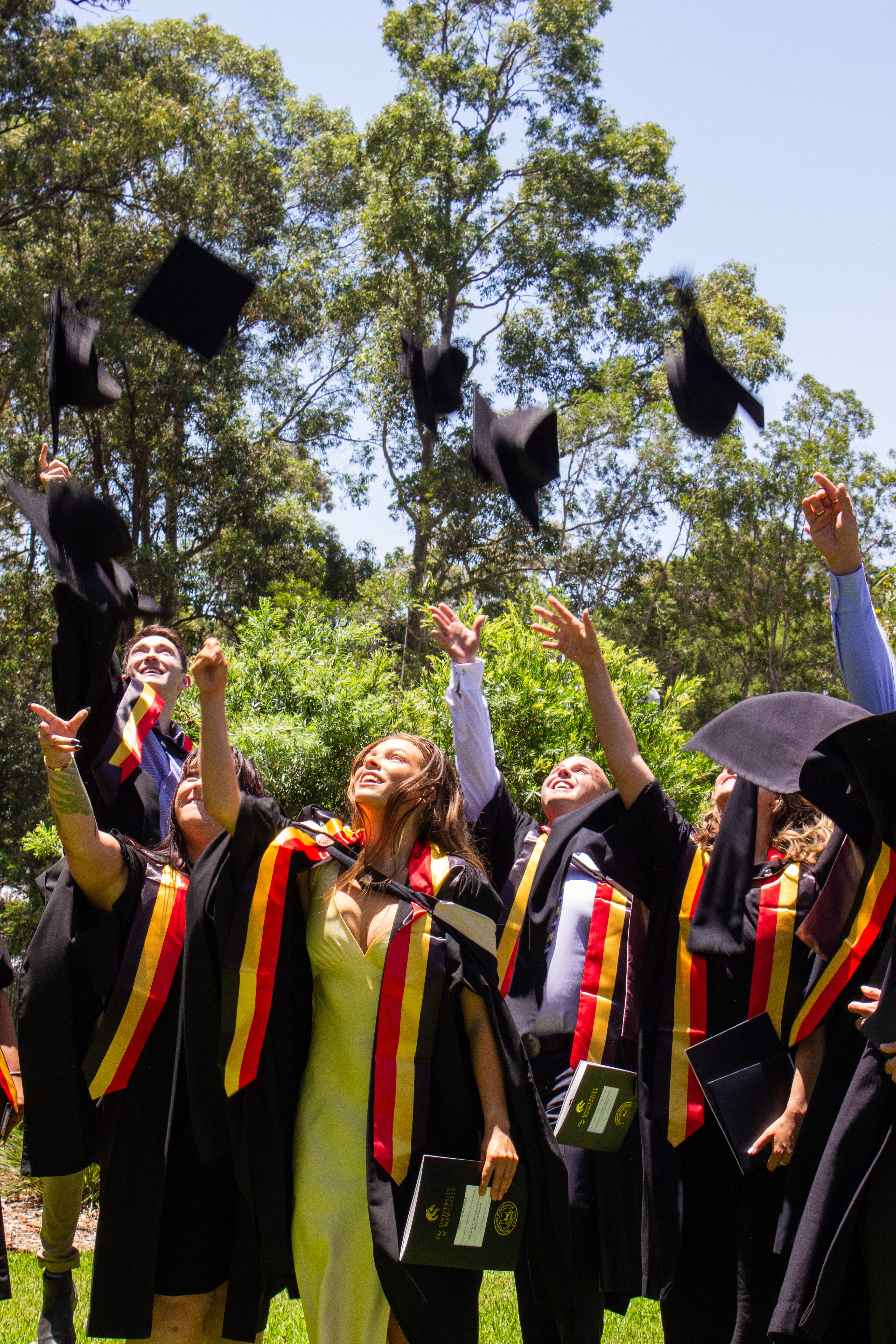 Group of graduating Indigenous doctors tossing their graduation caps in the air