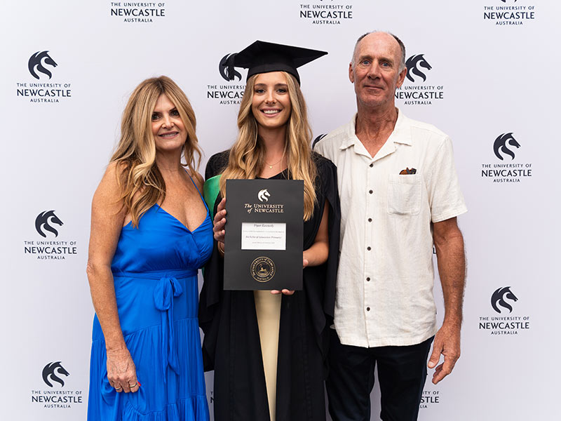 Piper Kennedy graduated with a Bachelor of Education (Primary) Piper stands in her graduation cap and gown smiling with her parents