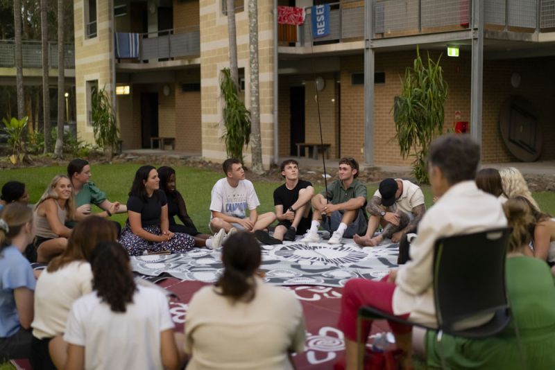 A group of people sitting on the ground in a circle