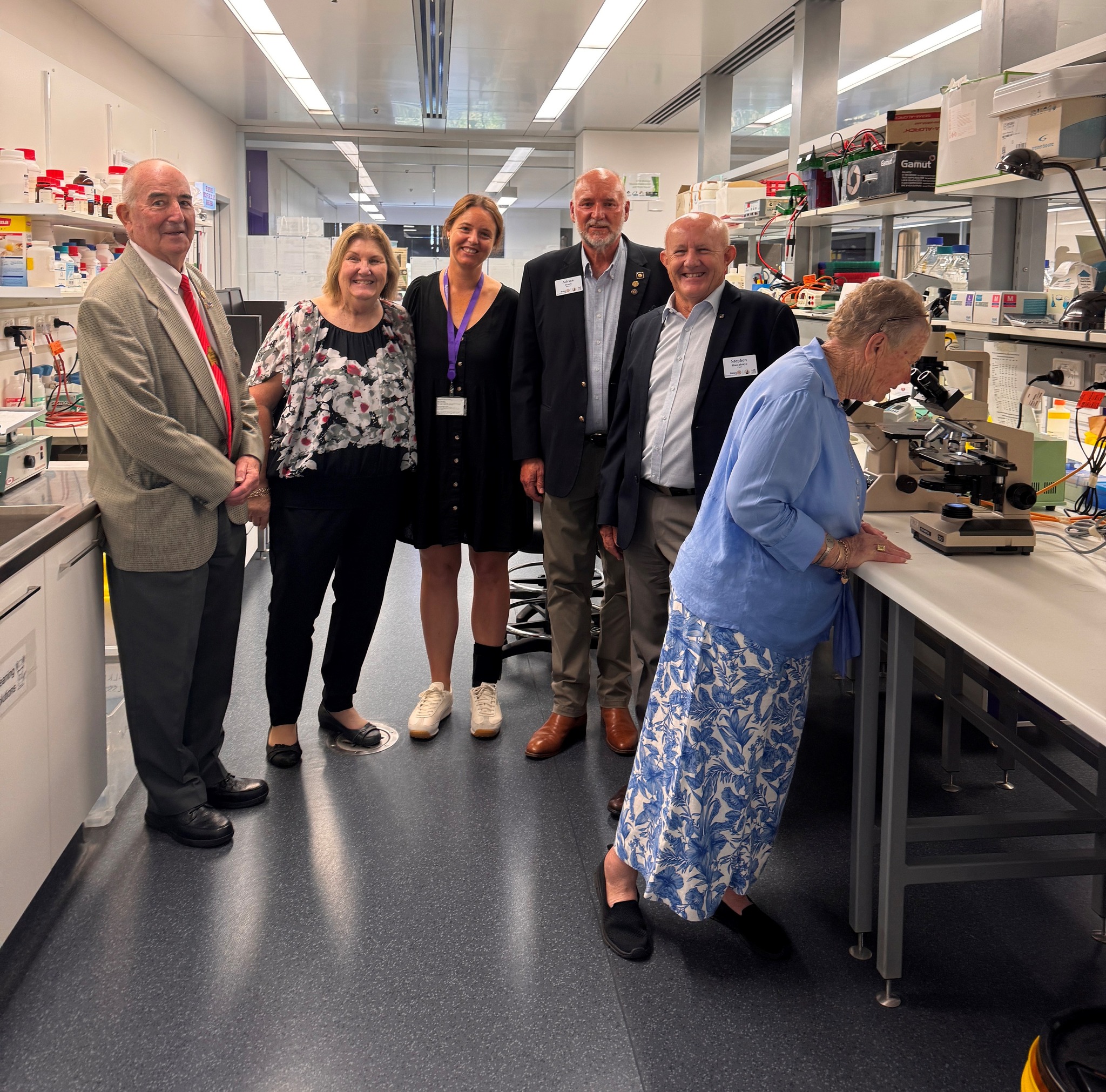 Margaret (far right) and Bob Ryan’s (far left) remarkable generosity through Australian Rotary Health is a testament to the power of community. They are shown here with (left to right) Australian Rotary Health CEO, Joy Gillett OAM, Dr Lucy Murtha, Australian Rotary Health Director, Adrian Roach and Australian Rotary Health Chair, PDG Stephen Humphreys A group of people in a laboratory, with one person viewing through a microsope