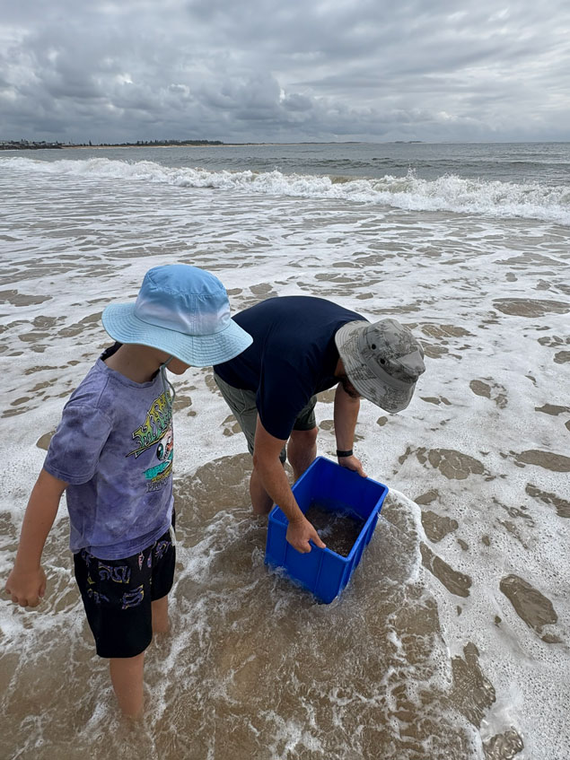 Community members put their blue buckets in the beach water