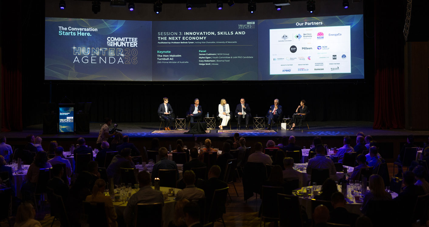 Six people sit on chairs on a stage, underneath a screen that displays sponsors, the Hunter Agenda 2026 logo, and the session name and panellists