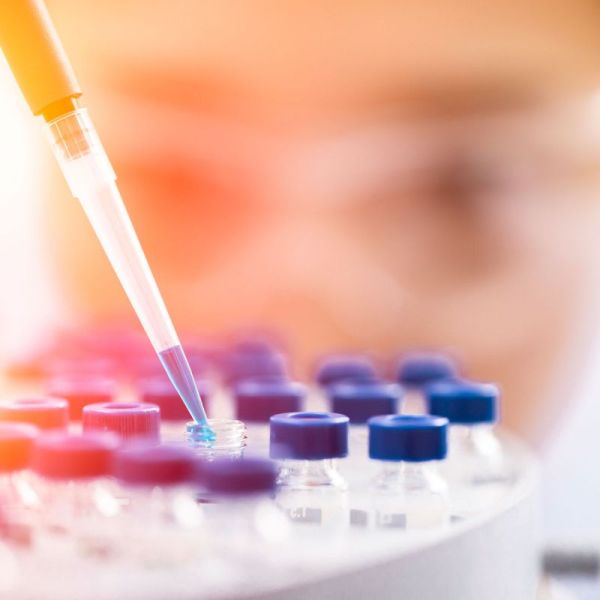 A dropper inserting blue liquid into a clear vial. $4m in NHMRC grants to transform healthcare and disease prevention.