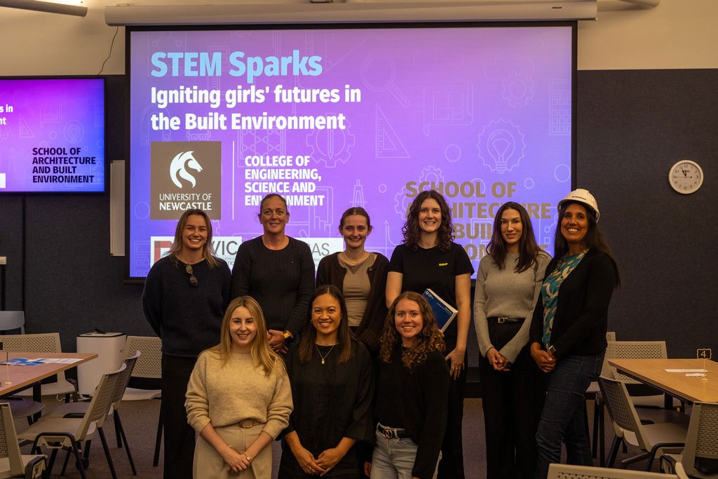 Nine women in STEM standing in front of projector 