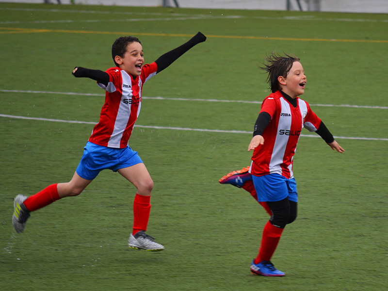 Two kids celebrate scoring a football goal