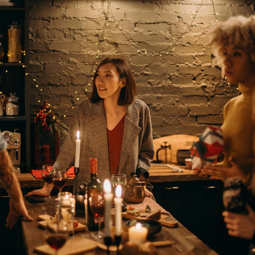 A lady standing around a table set for the Christmas season, taking with friends.